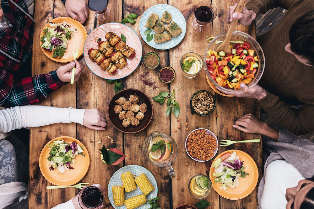 Enjoying dinner together. Top view of four people having dinner together while sitting at the rustic wooden table